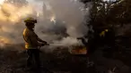 Petugas pemadam berupaya memadamkan api di lokasi jembatan yang terbakar di perbukitan Big Pines dekat Wrightwood, California. pada tanggal 12 September 2024. (ETIENNE LAURENT/AFP)