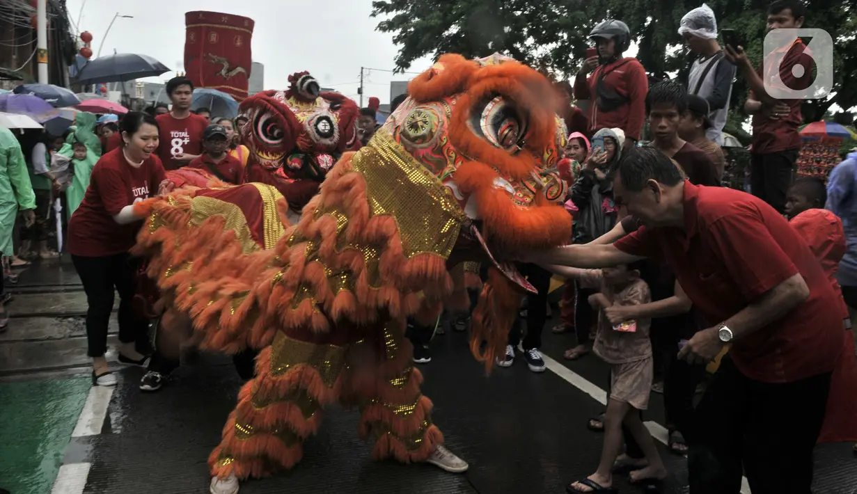 Warga memberikan angpau ke barongsai saat perayaan Cap Go Meh Tahun Baru Imlek 2571 di Jatinegara, Jakarta, Minggu (9/2/2020). Meski hujan, perayaan Cap Go Meh berlangsung meriah dengan atraksi barongsai dan liong serta arakan dewa-dewa mengelilingi kawasan Jatinegara. (merdeka.com/Iqbal S Nugroho)