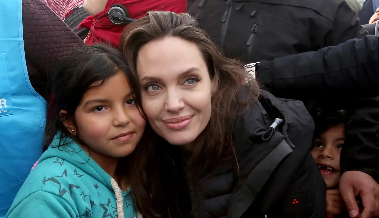 Utusan khusus lembaga pengungsi PBB, aktris Angelina Jolie berpose dengan seorang anak Suriah saat berkunjung ke Kamp Pengungsi Zaatari, di Mafraq, Yordania, Minggu (28/1). Jolie mengaku sedih saat bertemu dengan para pengungsi. (AP Photo/Raad Adayleh)