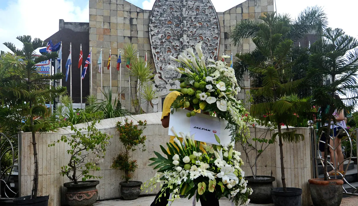 Seorang pria tampak membawa karangan bunga untuk memeperingati 13 tahun meledaknya bom bali 1 di depan monumen tragedi kemanusiaan,  Bali, Senin (12/10/2015). Hari ini tepat 13 tahun meledaknya bom bali 1. (AFP PHOTO/SONNY Tumbelaka)