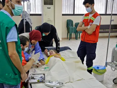 Staf medis merawat seorang pasien anak yang sedang dirawat akibat wabah Kolera di aula masjid yang diubah menjadi rumah sakit lapangan di Kota Bebnine, Distrik Akkar, Lebanon Utara, Rabu (26/10/2022). Awalnya Kementerian Kesehatan Masyarakat Lebanon memberi tahu WHO pada 6 Oktober 2022 tentang dua kasus Kolera yang dikonfirmasi laboratorium dan dilaporkan dari bagian utara negara itu. (AFP/Ibrahim Chalhoub)