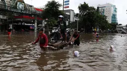 Pengendara sepeda motor menggunakan jasa angkut gerobak saat melintasi banjir di kawasan Green Garden, Jakarta Barat, Selasa (25/2/2020). Hujan yang mengguyur kawasan Jakarta membuat kawasan tersebut tergenang banjir setinggi 60-80 cm. (Liputan6.com/Johan Tallo)