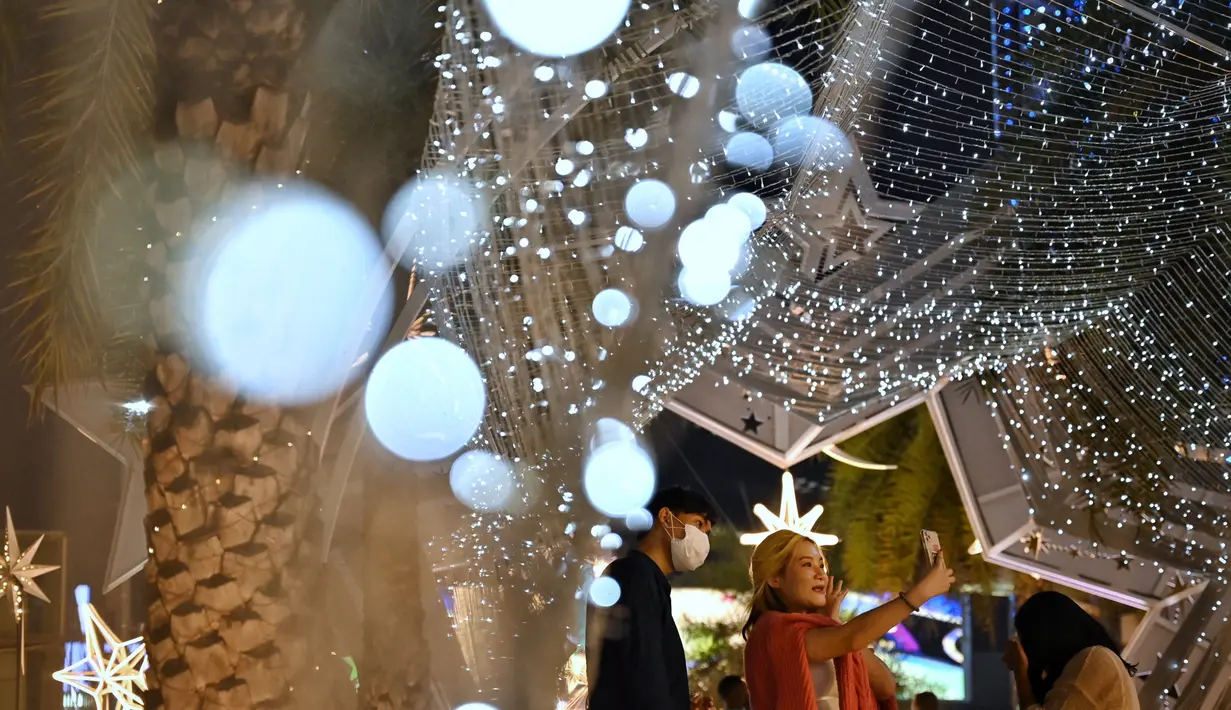 Orang-orang berfoto dengan dekorasi Natal di depan pusat perbelanjaan di Bangkok (21/12/2021). Menyambut Natal, dekorasi unik dan lucu ditampilkan di depan pusat perbelanjaan di Bangkok. (AFP/Lillian Suwanrumpha)