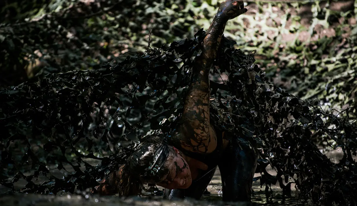 Seorang wanita melewati jaring yang dipenuhi lumpur saat mengikuti kompetisi Tough Viking di Stockholm, Swedia (12/5). Peserta harus melewati rintangan kawat berduri, lintasan api dan pendakian yang berat. (AFP/Jonathan Nackstrand)