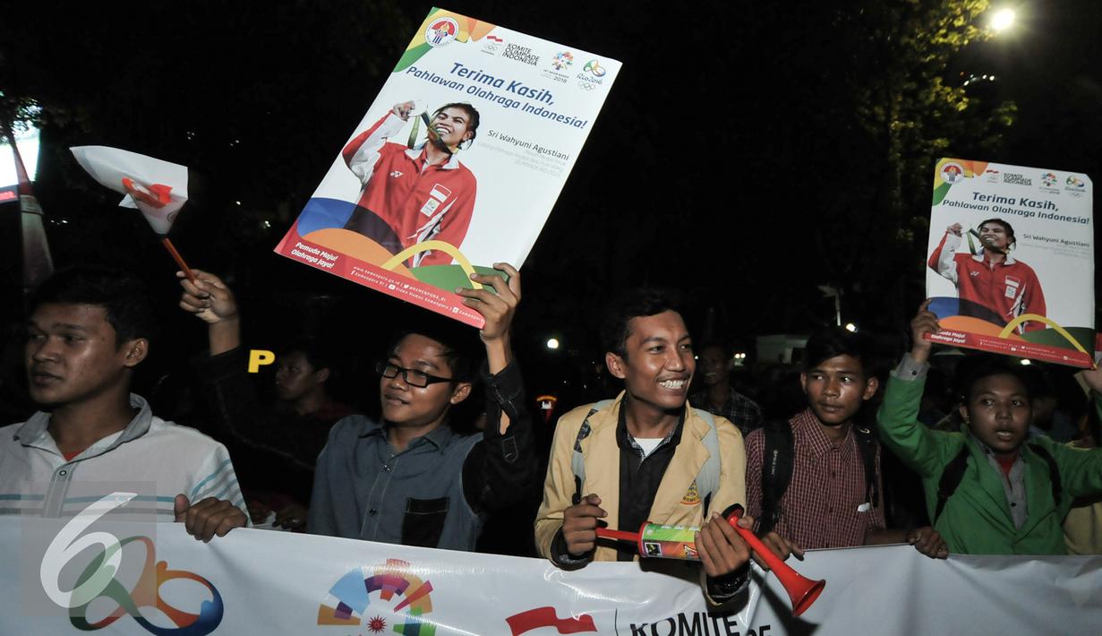 Antusias warga menyambut pahlawan olahraga Indonesia di kawasan Senayan, Jakarta, Selasa (23/8). Para atlet di arak menggunakan bus Bamdros menuju gedung Kementerian Pemuda dan Olahraga. (Liputan6.com/Yoppy Renato)