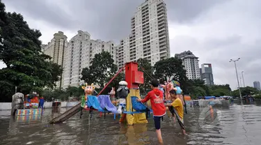 Sejumlah anak bermain di lahan bermain Kemayoran yang terendam banjir, Jakarta, Selasa (10/2). Tingginya curah hujan di wilayah Jakarta mengakibatkan sejumlah daerah masih terendam banjir. (Liputan6.com/Faizal Fanani)