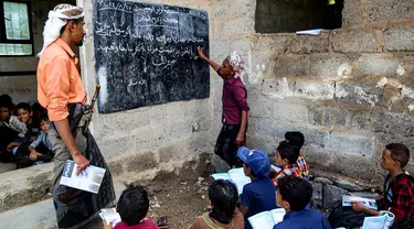 Seorang guru mengajar anak-anak dalam kelas agama di tempat terbuka di luar gedung yang sudah rapuh yang menjadi sekolah darurat di Mokha, provinsi barat Yaman, Taiz, pada 27 Agustus 2024. (Khaled ZIAD/AFP)