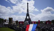 Seorang pria mengibarkan bendera Prancis di zona penggemar Olimpiade di Trocadero Gardens di depan Menara Eiffel di Paris, Minggu (8/8/2021). Pelepasan tongkat tuan rumah akan dibagi antara Stadion Olimpiade di Tokyo dan pesta publik dan konser di Paris. (AP Photo/Francois Mori)