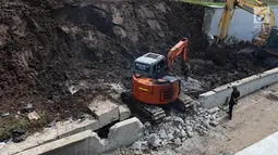 Alat berat menghancurkan beton untuk mengevakuasi mobil yang tertimbun longsor di Underpass Perimeter, Bandara Soetta, Tangerang, Banten, Selasa (6/2). Enam alat berat dikerahkam untuk proses tersebut. (Liputan6.com/Angga Yuniar)