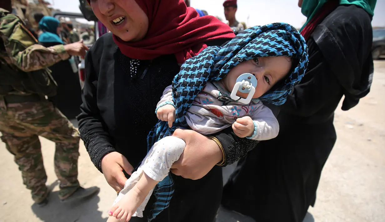 Warga sipil Irak menggendong anaknya saat mengungsi dari Kota Tua di Mosul, 1 Juli 2017. Dana Anak PBB (UNICEF) pada 29 Juni 2017, mengatakan ribuan anak telah terjebak di daerah yang masih dikuasai ISIS di pusat kota tua itu. (AHMAD AL-RUBAYE/AFP)