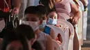 Anak-anak mengantre untuk vaksin covid-19 CoronaVac di San Lorenzo, Paraguay, Senin (31/1/2022). Paraguay mulai memvaksinasi anak-anak berusia 5 hingga 11 tahun pada hari Senin, karena peningkatan tajam infeksi covid-19 yang didorong oleh varian omicron. (NORBERTO DUARTE / AFP)