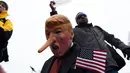 Topeng mirip Trump dengan hidung panjang mirip tokoh kartun Pinokio dikenakan demonstran saat aksi sebagai bentuk sindiran untuk Trump di Washington DC, Jumat (20/1). (AFP PHOTO / Jewel SAMAD)