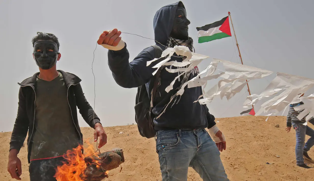 Warga Palestina bersiap menerbangkan layang-layang yang telah diberikan bom molotov di atas pagar perbatasan dengan Israel, di pinggiran timur Kota Gaza (20/4). Unjuk rasa warga Palestina terhadap Isrel memasuki minggu keempat. (AFP Photo/Mohammed Abed)