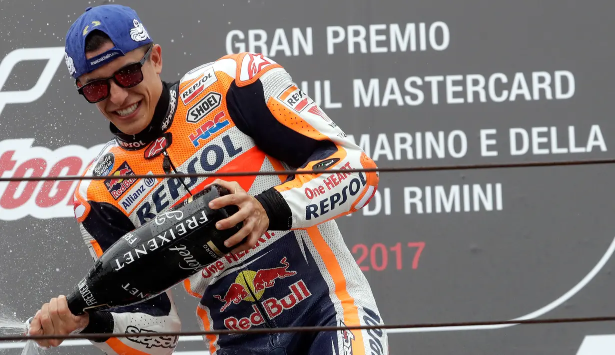 Pembalap Repsol Honda, Marc Marquez menyemprotkan sampanye saat merayakan kemenangannya di atas podium MotoGP San Marino 2017 di Italia, Minggu (10/9). Marquez sukses mencatat waktu 50 menit 41,565 detik, terpaut 1,192 detik. (AP Photo/Antonio Calanni)