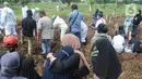 Keluarga menyaksikan pemakaman jenazah korban COVID-19 di TPU Tegal Alur, Jakarta, Kamis (17/12/2020). Hingga hari ini, intensitas pemakamanan korban covid-19 di DKI masih tinggi dengan rata-rata yang dimakamkan mencapai 30 hingga 38 jenazah per hari. (merdeka.com/Arie basuki)