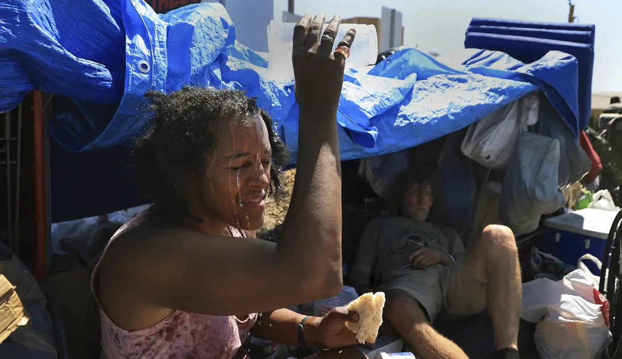 Di tengah panas 112 derajat, Angel Martinez menggunakan sisa airnya untuk mendinginkan diri di perkemahannya bersama Jerry Fullington di sepanjang Santa Rosa Ave., Senin, 5 September 2022, di Santa Rosa, California (Kent Porter/The Press Demokrat via AP)