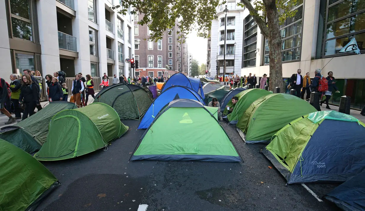 Aktivis iklim mendirikan tenda saat berkemah di jalan utama Westminster, London, Inggris, Selasa (8/10/2019). Aksi yang bertujuan mendesak pemerintah mengekang emisi karbon tersebut bagian dari gerakan Pemberontakan Kepunahan. (Jonathan Brady/PA via AP)
