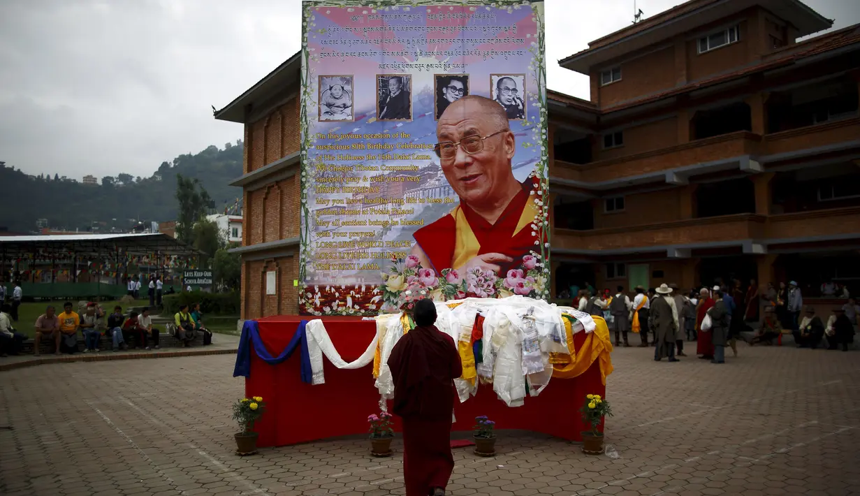 Seorang biksu Tibet berdoa di depan potret Dalai Lama saat perayaan ulang tahun ke-80 di Kathmandu, Nepal (6/7/2015). Dalai lama merupakan nama gelar dari agama Budha, gelar  ini diturunkan secara turun temurun. (REUTERS/Navesh Chitrakar)