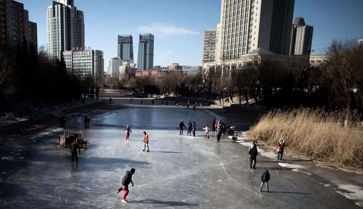 Sejumlah warga bermain ice skating di sungai yang membeku di Beijing, China (21/1). Akibat membeku, Sungai ini menjadi objek wisata dadakan yang banyak diminati wisatawan. (AFP/Fred Dufour)