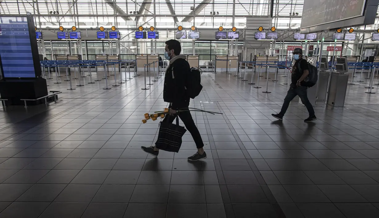 Beberapa penumpang berjalan di dalam bandara internasional Arturo Merino Benitez yang sepi pada hari pertama pemerintah menutup perbatasan di Santiago, Chile, Senin (5/4/2021). Kasus COVID-19 telah melonjak di Chile meskipun ada upaya vaksinasi. (AP Photo/Esteban Felix)