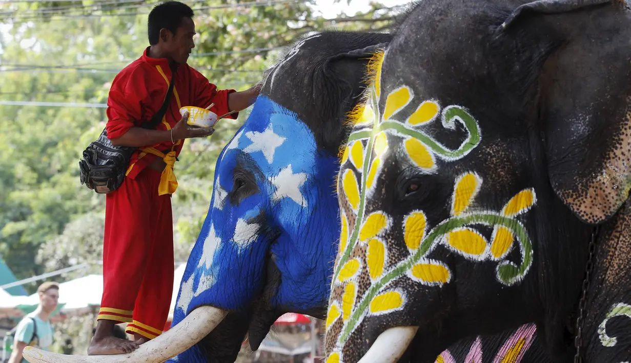 Seorang Pawang menaiki gading gajah saat festival air Songkran di Ayutthaya, Bangkok, Thailand (10/4/2015). Festival air songkoran menandai dimulainya Tahun Baru tradisional Thailand. (REUTERS/Chaiwat Subprasom)