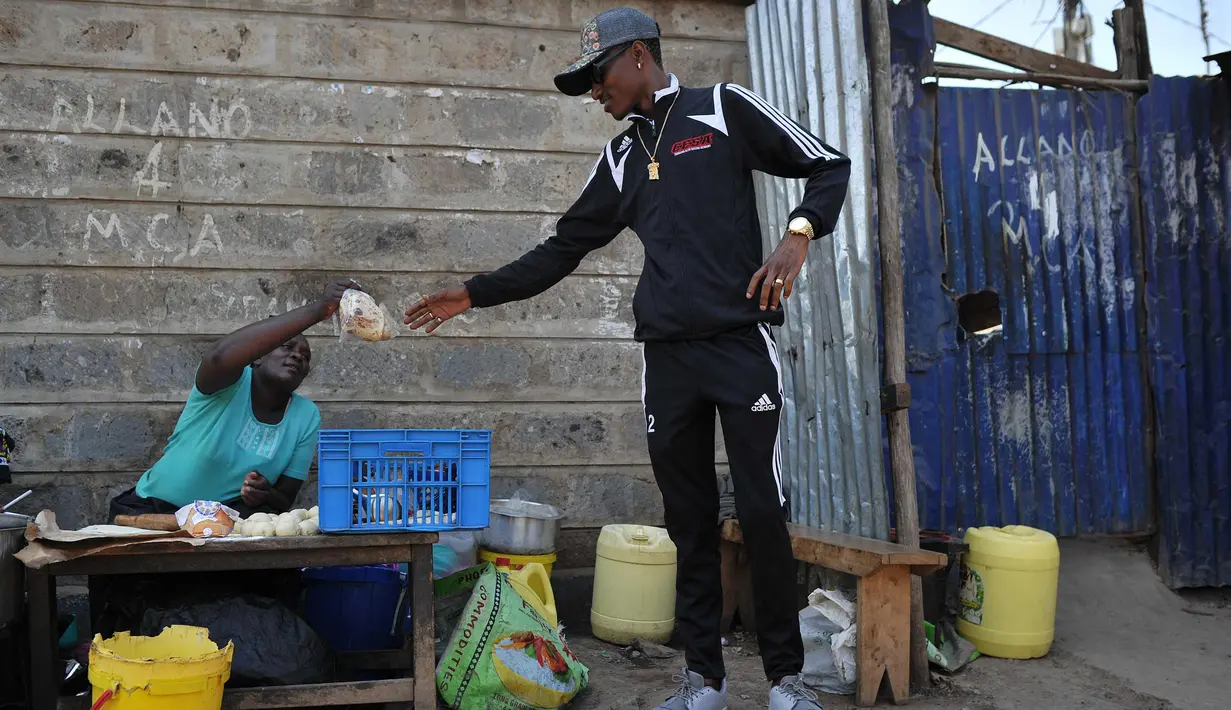 Artis hip hop Kenya Henry Ohanga alias Octopizzo yang berasal dari Kibera kumuh terbesar di Kenya di Nairobi, membeli makanan ringan dari penjual pinggir jalan saat berkunjung ke Kibera pada 16 Januari 2018. (AFP Photo/Tony Karumba)