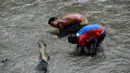 Dua pria mencari logam berharga di Sungai Guaire, di Caracas, Venezuela (1/2). Puluhan warga mencari logam atau tembaga setiap hari di Sungai Guaire, tempat selokan Caracas mengalir.  (AFP Photo/Federico Parra)