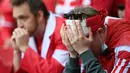 Fans bereaksi di antara kerumunan setelah gelandang timnas Denmark Christian Eriksen pingsan di lapangan pada laga Denmark vs Finlandia di Grup B Euro 2020 di Parken Stadium, Copenhagen, Sabtu (12/6/2021). (Jonathan NACKSTRAND / various sources / AFP)