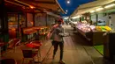Pramusaji membersihkan makanan dari meja, yang biasanya dilakukan oleh pengujung, di pasar Naschmark di Wina, Austria pada 5 Oktober 2020. Naschmarkt adalah pasar tertua, terbesar, dan terpopuler di Wina kini sepi pengunjung akibat pandemi corona COVID-19. (JOE KLAMAR / AFP)