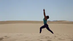 Seorang wanita mengikuti kelas yoga yang digelar di gurun Samalayuca, negara bagian Chihuahua, Meksiko, 28 April 2018. Ratusan penggemar yoga mengikuti latihan bersama di bawah terik matahari dan beralaskan pasir. (AFP PHOTO / HERIKA MARTINEZ)