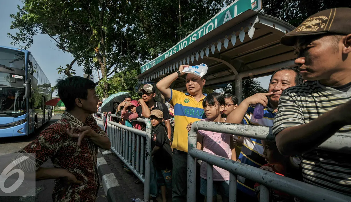 Antrian warga menunggu kedatangan bus tngkat City Tour Wisata Keliling Jakarta di halte Istiqlal, Jakarta, Kamis (7/7). Sejumlah warga memanfaatkan fasilitas bus wisata gratis untuk berkeliling Jakarta bersama keluarga. (Liputan6.com/Yoppy Renato)