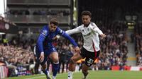 Pemain Chelsea, Pedro Neto, berebut bola dengan bek sayap Fulham, Antonee Robinson, dalam laga pekan ke-33 Premier League 2024/2025 di Craven Cottage, Minggu (20/4/2025). Chelsea menang 2-1 dalam laga tersebut. (Jonathan Brady/PA via AP)