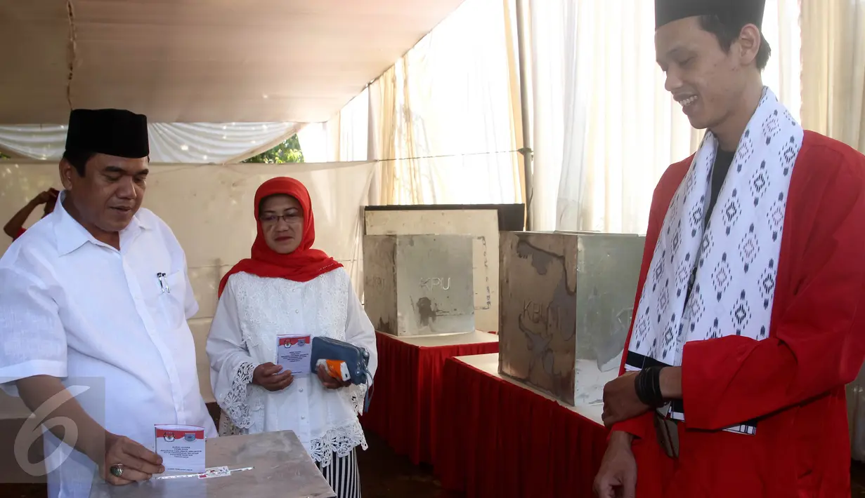 Calon Walikota Tangerang Selatan nomor urut 2 Arsid dan istri memasukan surat suara ke kotak saat menggunakan hak pilih di TPS 31 Kelurahan Pondok Benda, Tangsel, Rabu (9/12). Arsid merupakan pemilih perdana pada TPS tersebut. (Liputan6.com/Fery Pradolo)