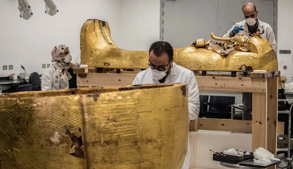 Para arkeolog merestorasi sarkofagus atau peti mati emas Firaun Tutankhamun di laboratorium restorasi Grand Egyptian Museum (GEM), Giza, Mesir, Senin (13/4/2020). Firaun Tutankhamun merupakan Raja Mesir Kuno yang memerintah antara tahun 1342-1325 SM. (Khaled DESOUKI AFP)