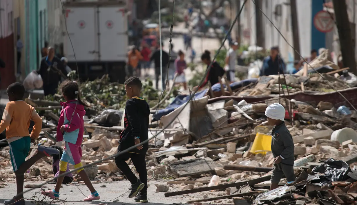 Sejumlah anak berjalan di tengah puing-puing bangunan setelah badai tornado menghantam Regla, Kuba (28/1). Hantaman tornado juga merobohkan tiang-tiang listrik di daerah tersebut. (AP Photo/Ramon Espinosa)