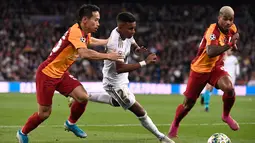 Pemain Real Madrid Rodrygo (tengah) melewati pemain Galatasaray Yuto Nagatomo (kiri) dan Mario Lemina (kanan) pada pertandingan Grup A Liga Champions di Stadion Santiago Bernabeu, Madrid, Spanyol, Rabu (6/11/2019). Rodrygo mencetak tiga gol ke gawang Galatasaray. (PIERRE-PHILIPPE MARCOU/AFP)