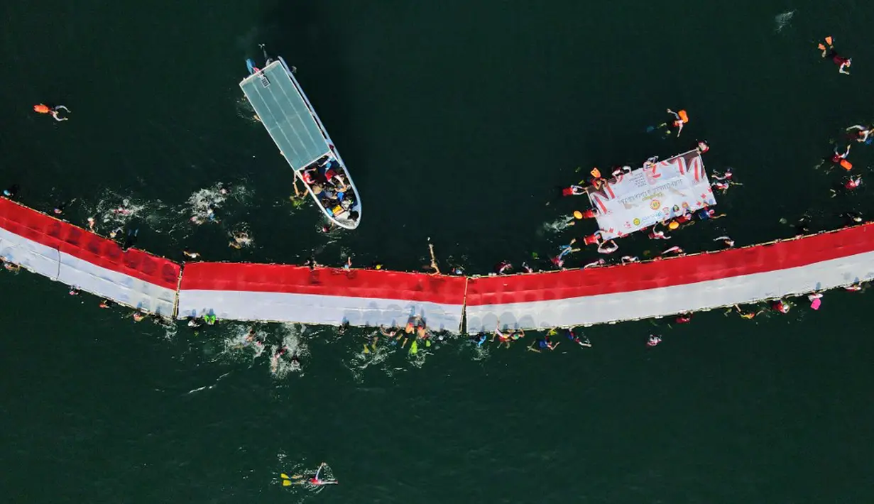 Para perenang dari Makassar Watersports Community dan klub-klub renang serta personel Kantor Pencarian dan Pertolongan dan Kepolisian Perairan berpartisipasi dalam kegiatan pembentangan bendera Merah Putih dari Dermaga Kayu Bangkoa, yang dilanjutkan dengan pengarakan bendera sampai ke Pulau Gusung. (Muchtamir ZAIDE/AFP)