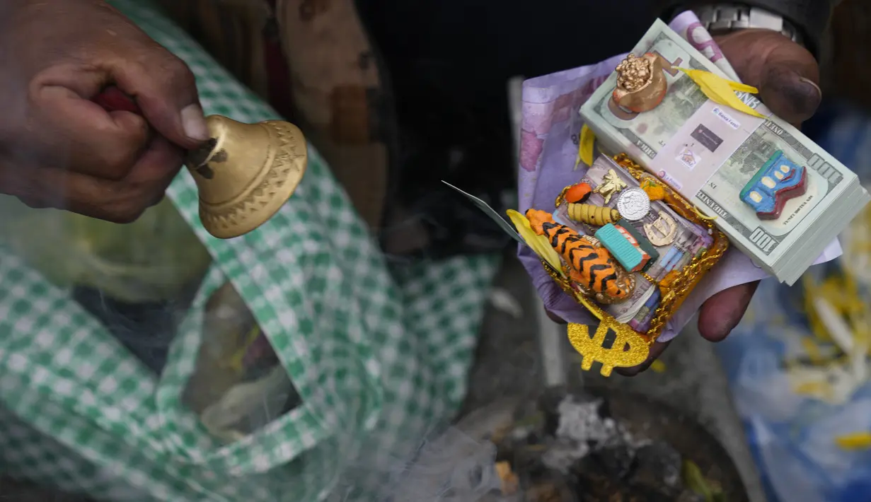 Pemandu spiritual Aymara memberkati barang-barang mini dan uang palsu selama Alasitas Fair tahunan di La Paz, Bolivia pada 24 Januari 2022. Orang-orang membeli replika kecil dari barang-barang yang ingin mereka peroleh sepanjang tahun, seperti rumah, mobil, dan kekayaan. (AP Photo/Juan Karita)