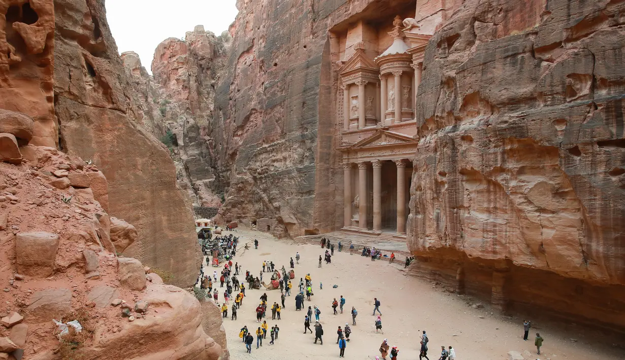 Wisatawan jalan-jalan saat mengunjungi kota arkeologi Petra, Yordania, Kamis (21/11/2019). Petra ditetapkan sebagai salah satu dari Tujuh Keajaiban Dunia Baru oleh Yayasan New7Wonders pada tahun 2017. (AHMAD ABDO/AFP)