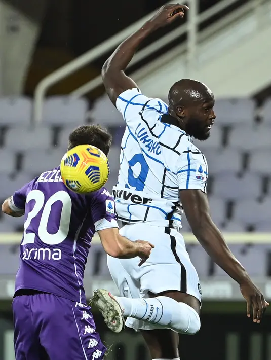 Bek Fiorentina, Pezzella (Kiri) dan penyerang Inter Milan, Romelu Lukaku bersaing berebut bola pada lanjutan laga Liga Italia di Stadion Artemio Franchi, Sabtu dinihari WIB (6/2/2021). Inter Milan mengalahkan Fiorentina 2-0 dan menggusur AC Milan dari puncak klasemen Serie A.  (Alberto PIZZOLI/AFP)