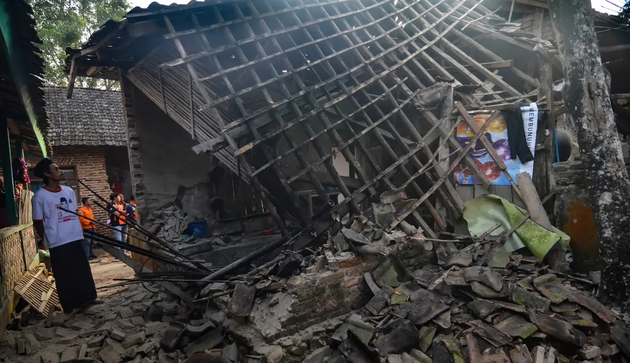 Warga melihat rumah yang rusak usai gempa melanda Pandeglang, Banten, Sabtu (3/8/2019). Menurut Kepala BPBD Kabupaten Pandegelang Deni Kurnia, untuk di wilayah Pandeglang kerusakan terparah usai gempa Banten terjadi di Desa Panjang Jaya dan Sinar Jaya, Kecamatan Mandalawangi. (RONALD SIAGIAN/AFP)