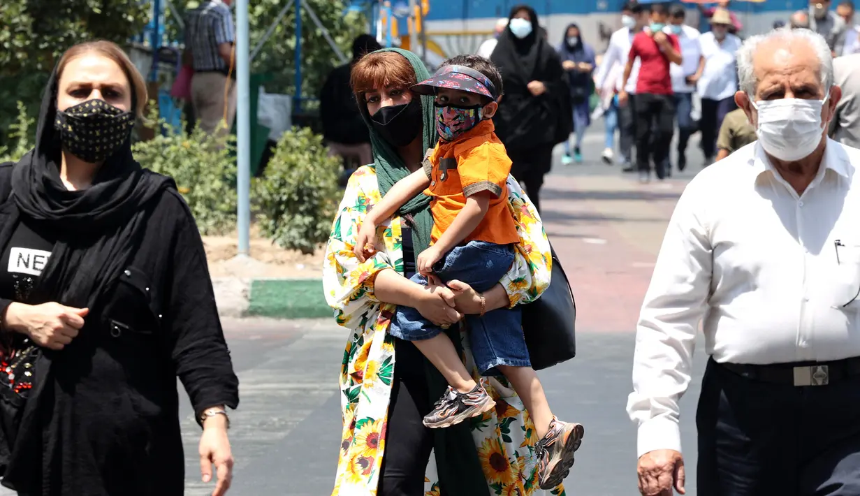 Warga Iran mengenakan masker saat mereka berjalan di sepanjang jalan di ibu kota Teheran, Sabtu (3/7/2021). Presiden Hassan Rouhani mengaku khawatir Iran akan dilanda gelombang kelima pandemi Covid-19 karena kemunculan virus corona varian Delta. (ATTA KENARE/AFP)