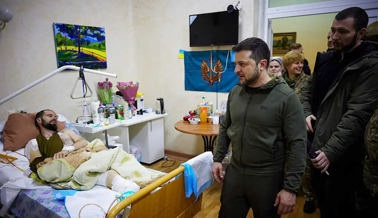 Dalam foto yang disediakan oleh Kantor Pers Kepresidenan Ukraina pada 13 Maret 2022, Presiden Ukraina Volodymyr Zelenskyy (tengah) berjalan melewati seorang tentara yang terluka saat kunjungannya ke sebuah rumah sakit di Kiev, Ukraina. (Ukrainian Presidential Press Office via AP)