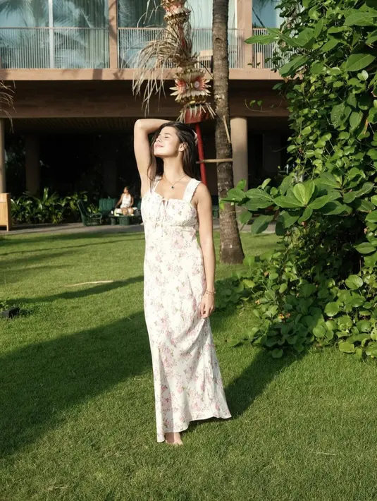 Ia tampak kenakan dress putih dengan motif bunga yang begitu manis. [Foto: Instagram/ Maria Theodore]