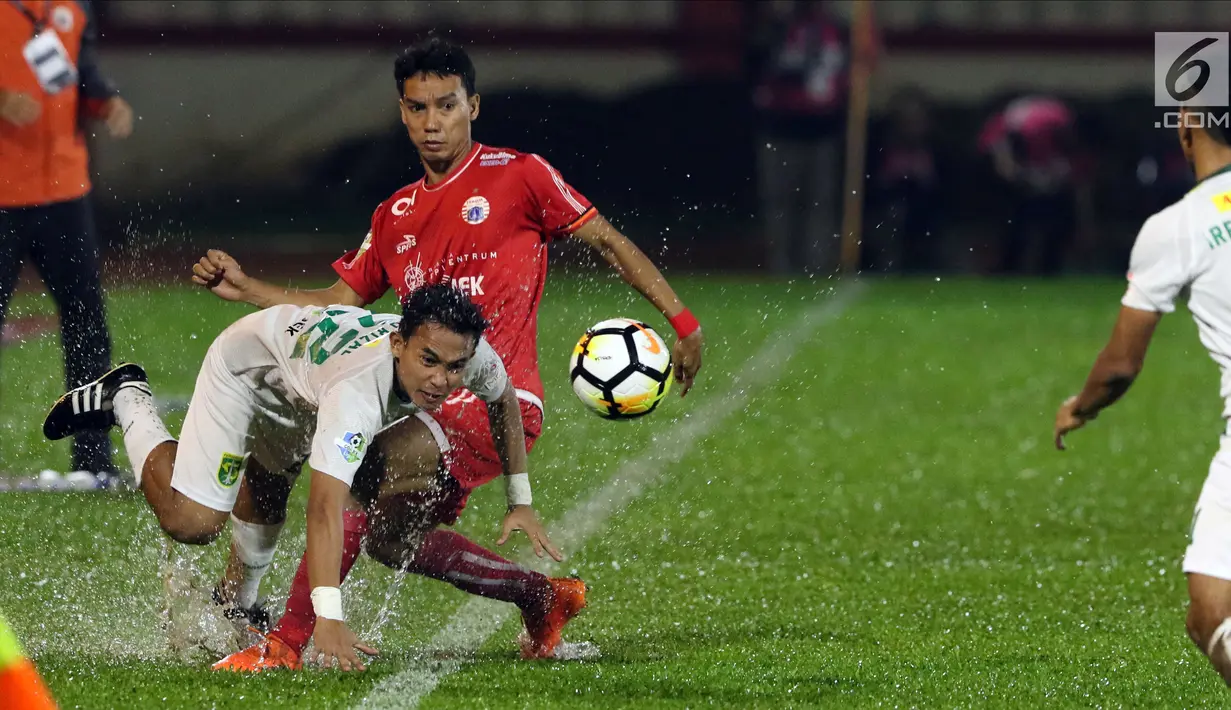 Gelandang Persija, Novri Setiawan mencoba menahan pemain Persebaya, Abu Rizal Maulana pada lanjutan Go-Jek Liga 1 Indonesia 2018 bersama Bukalapak di Lapangan PTIK, Jakarta, Selasa (26/6). (Liputan6.com/Helmi Fithriansyah)