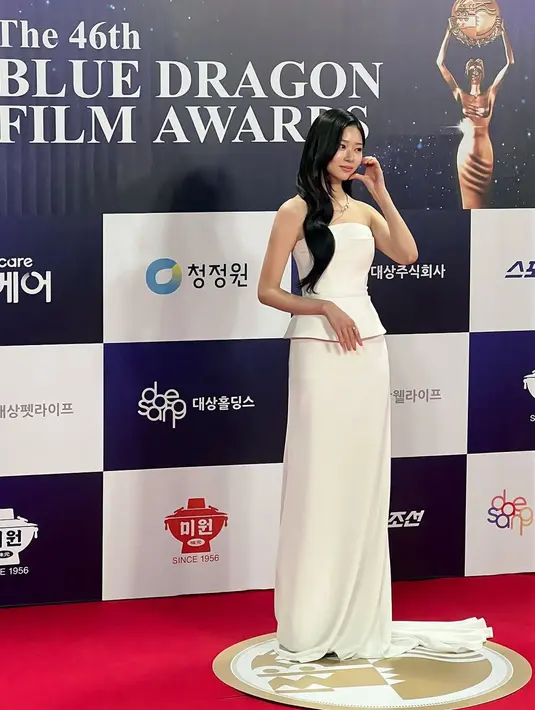 <p>Kim Min Ju tampil mengenakan setelan putih dari atasan strapless dipadukan rok panjang menyapu lantai serta kalung tanpa liontin. Rambut panjang hitam terurai tanpa poni. [@management_soop]</p>