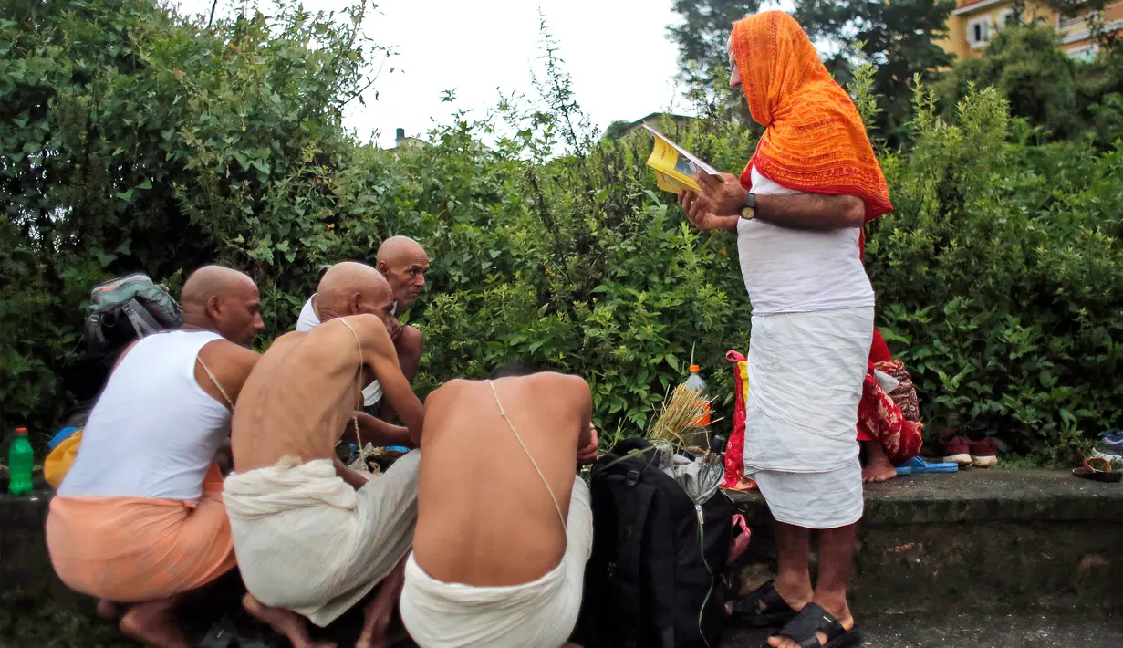Umat Hindu Nepal melakukan ritual dibimbing oleh pemuka agama di kuil Hindu Gokarneshwar, Kathmandu, Nepal (21/8). Anak laki-laki dan perempuan yang ayahnya masih hidup, wajib menghabiskan waktu bersama dengan membawa hadiah. (Niranjan Shrestha/AP)