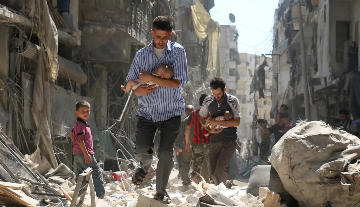 Para pria menggendong bayi saat berjalan melewati puing-puing bangunan yang hancur usai serangan udara di daerah yang dikuasai pemberontak di Salihin, Aleppo, Suriah, 11 September 2016. (Photo by Ameer al-HALBI/AFP)