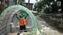 Petugas UPK Badan Air DLH DKI Jakarta saat merapikan instalasi botol yang menghiasi pos di Pasar Rebo, Jakarta, Selasa (12/3). Lebih dari seribu botol plastik bekas dipasang untuk menghiasi Pos  UPK Badan Air di Pasar Rebo. (merdeka.com/Iqbal Nugroho)