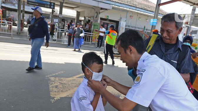 Petugas memasangkan masker ke seorang anak saat sosialisasi pencegahan virus  corona yang digelar PT KAI Daop 1 melalui Rail Clinic  di stasiun kereta Depok, Jumat (6/3/2020).  (Liputan6.com/Herman Zakharia)